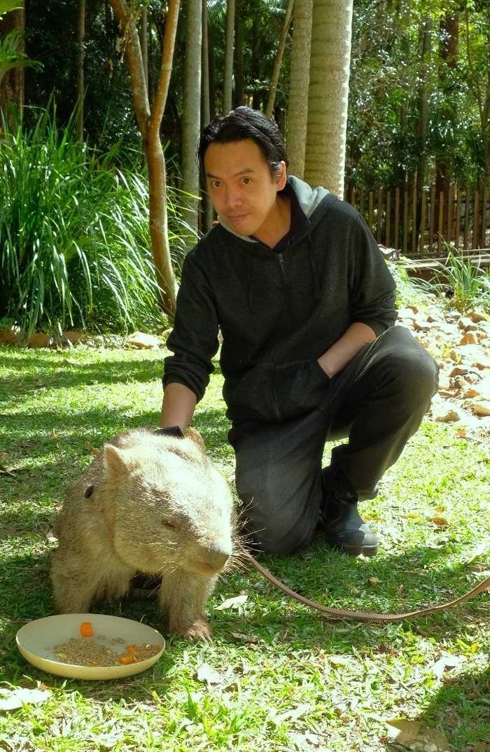 Paddy crouched beside a wombat at a wildlife park